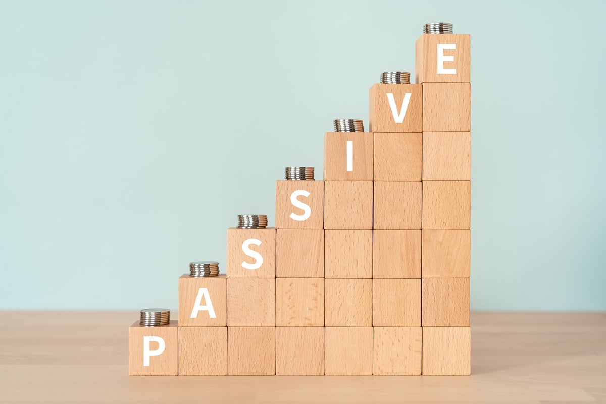 Ascending building blocks that read the word "passive" with coins on top of each letter to symbolize passive income. 