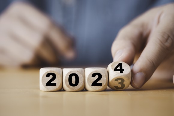 A hand turning dice to 2024.