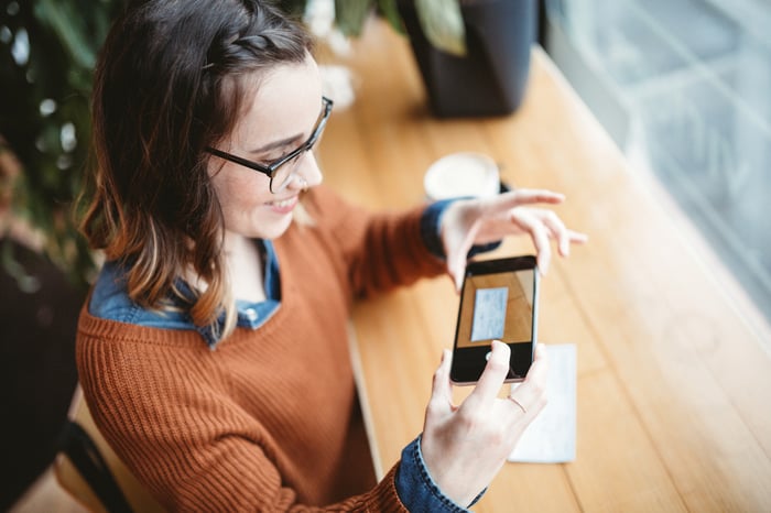 Person taking picture of check with smartphone.
