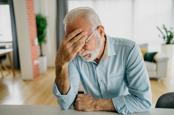 A seated person holding their head.