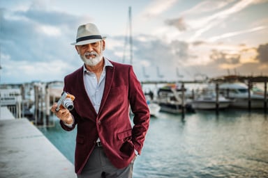 wealthy senior posing with a cocktail near boats