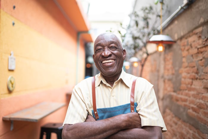 Person with arms crossed, smiling broadly.