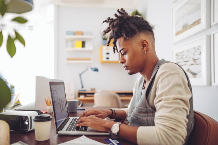 A person sitting at a desk and typing on a computer. 