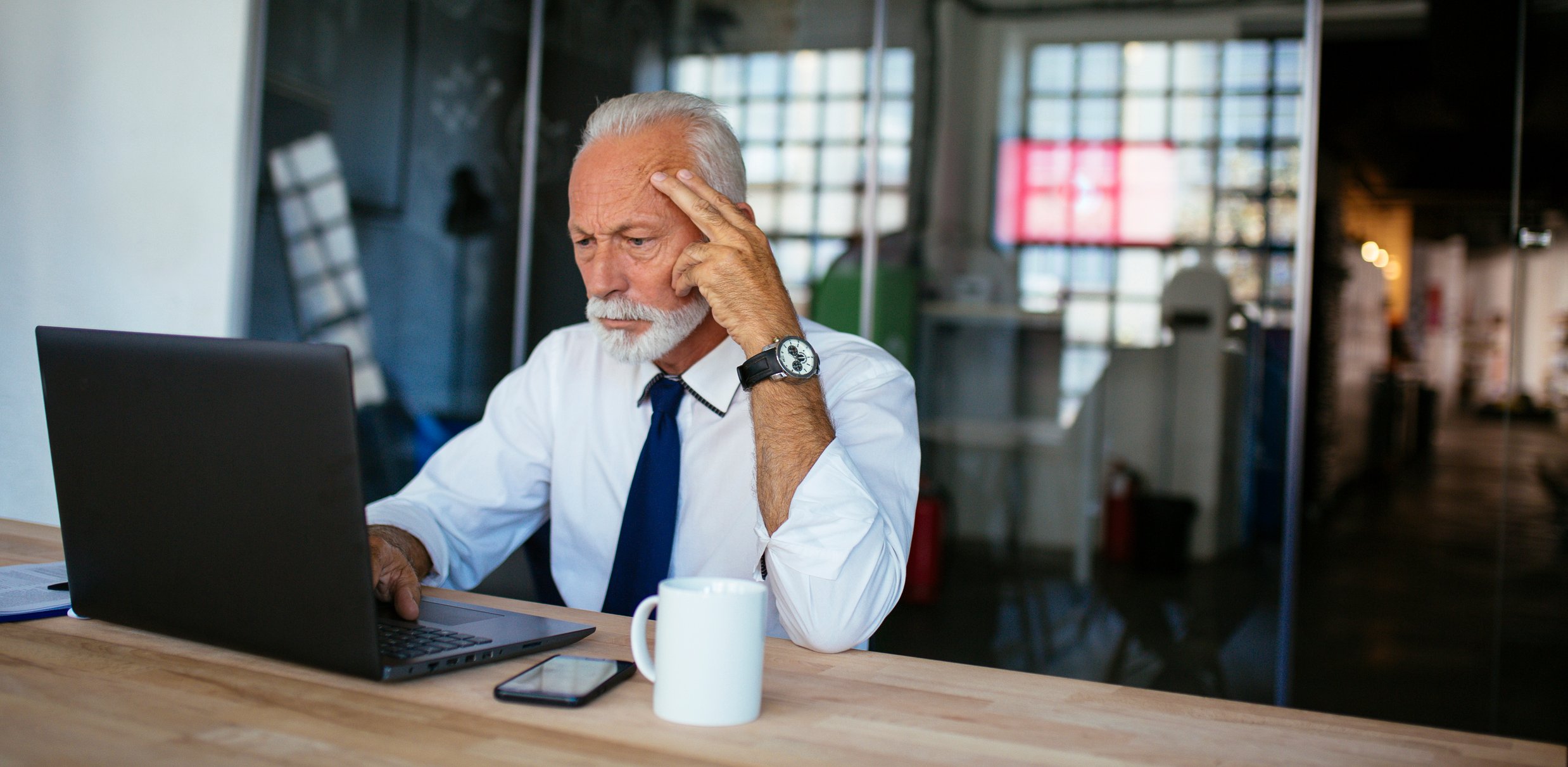 A person with a serious expression looking at a laptop.
