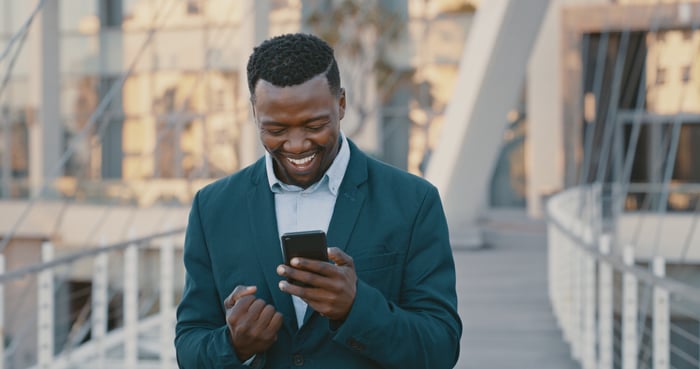 Guy pumps his fist at his smartphone. 