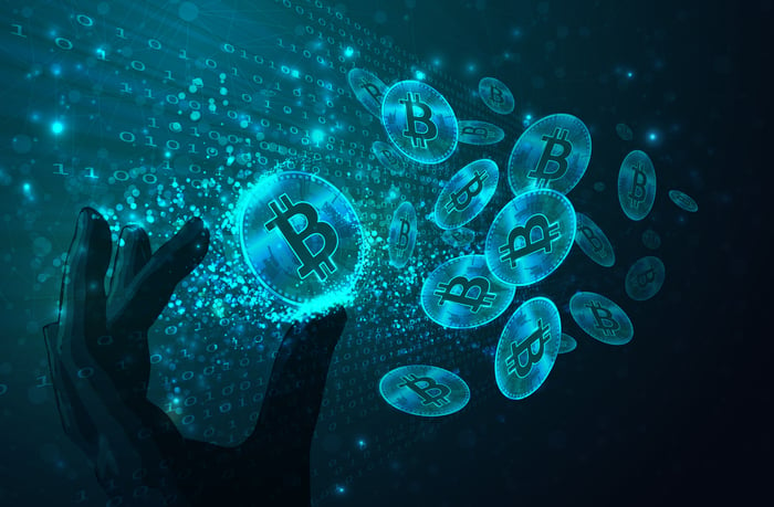 Hand reaching for glowing blue bitcoins.