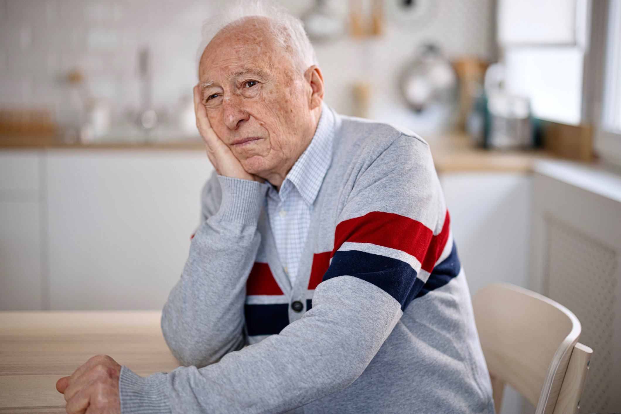 A person sitting at a kitchen table with a sad expression.