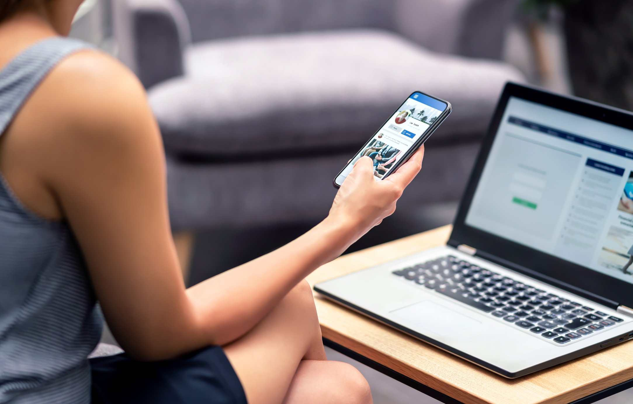 A person on their phone in front of a computer.