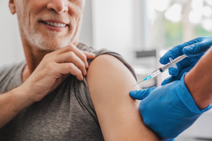 A person smiles while receiving a vaccine.