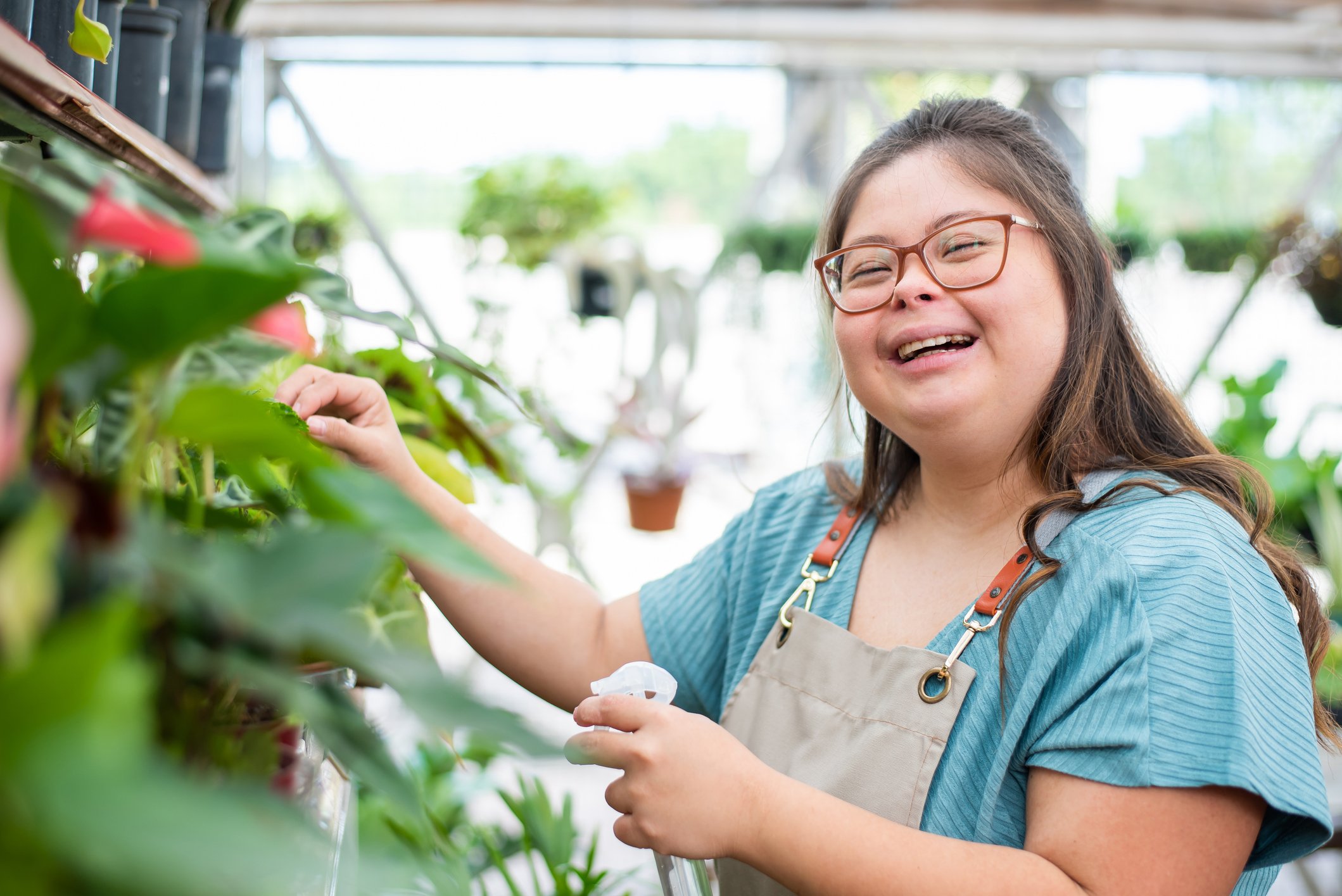Someone is tending plants in a greenhouse, and smiling.
