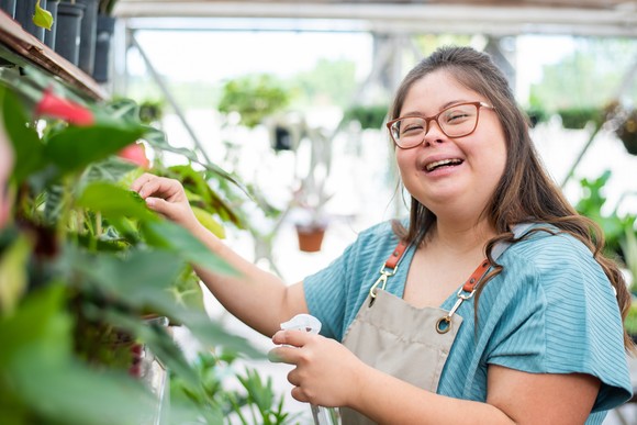 Someone is tending plants in a greenhouse, and smiling.