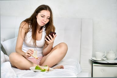 Person in undershirt using a smartphone in bed