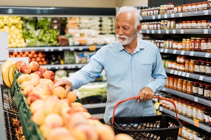 A person in a supermarket produce aisle.