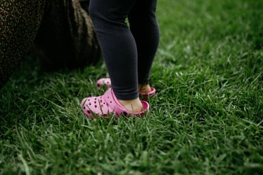 wearing pink crocs standing in grass