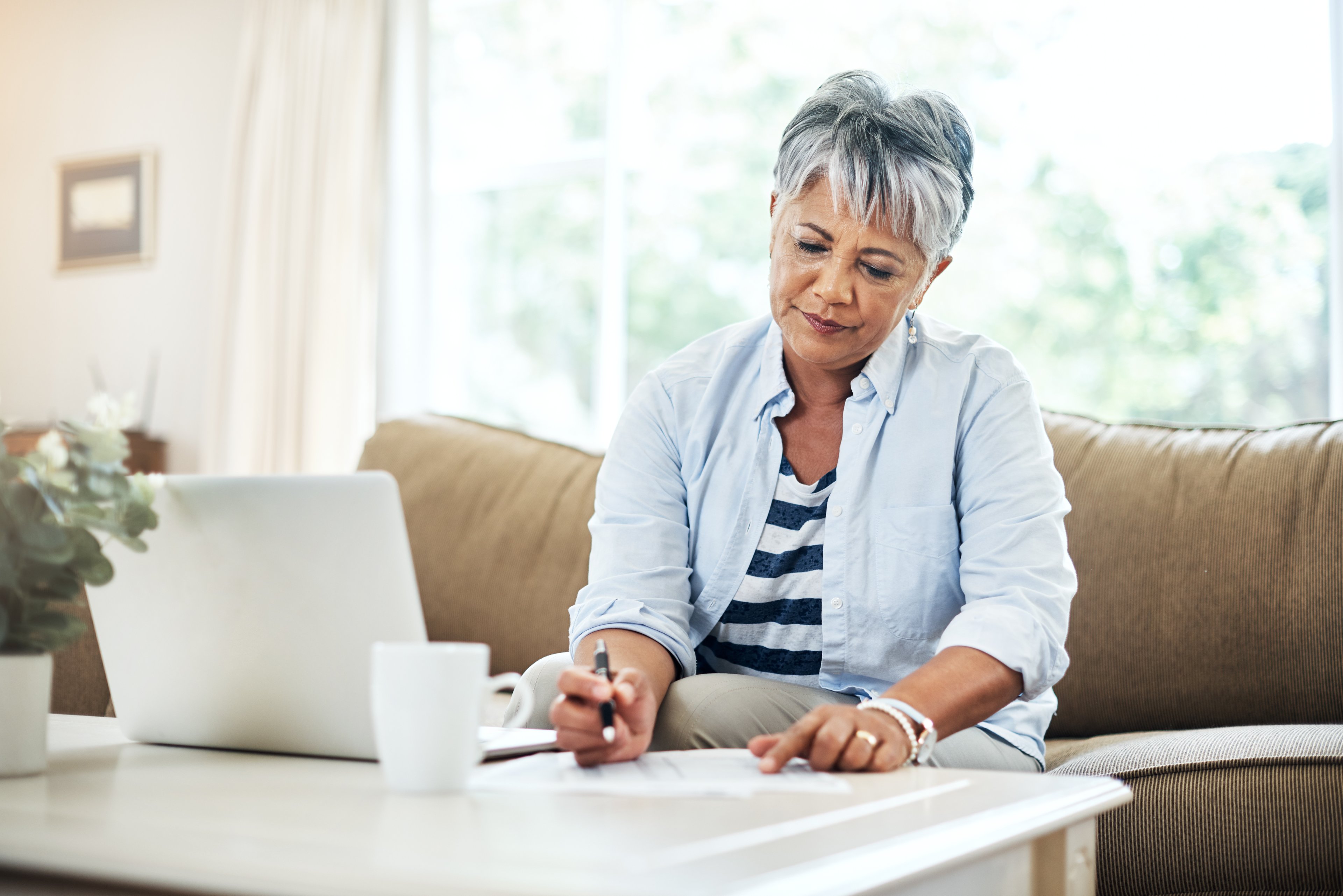 A person at a table with a laptop holding a pen.