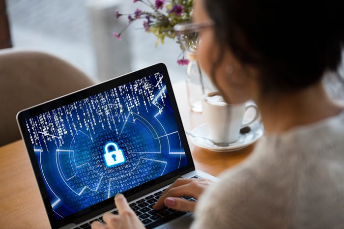 Woman in front of laptop with cybersecurity icon on it. 