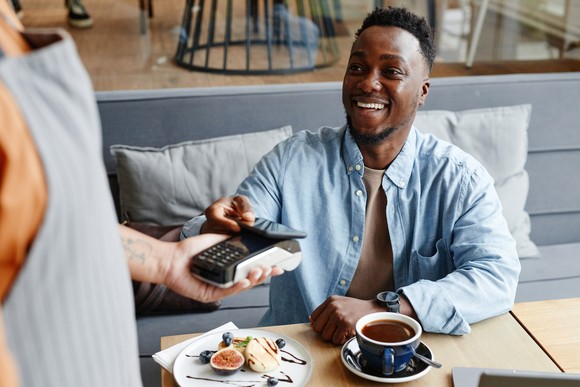 A person using their phone to pay a bill at a restaurant.