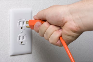 A hand plugging or unplugging a power cord