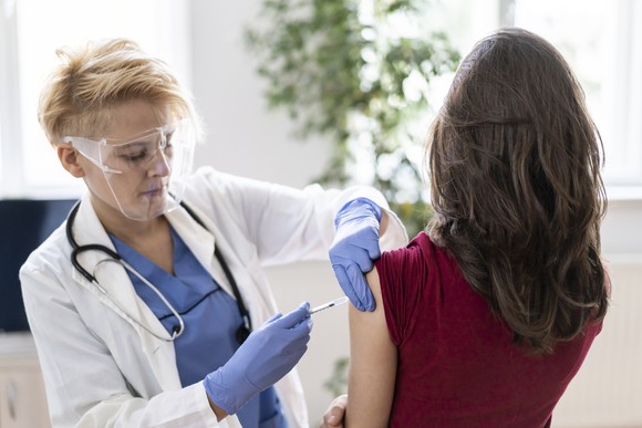 A healthcare worker vaccinates a person in a medical office.