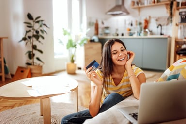 A person holding a credit card with a computer