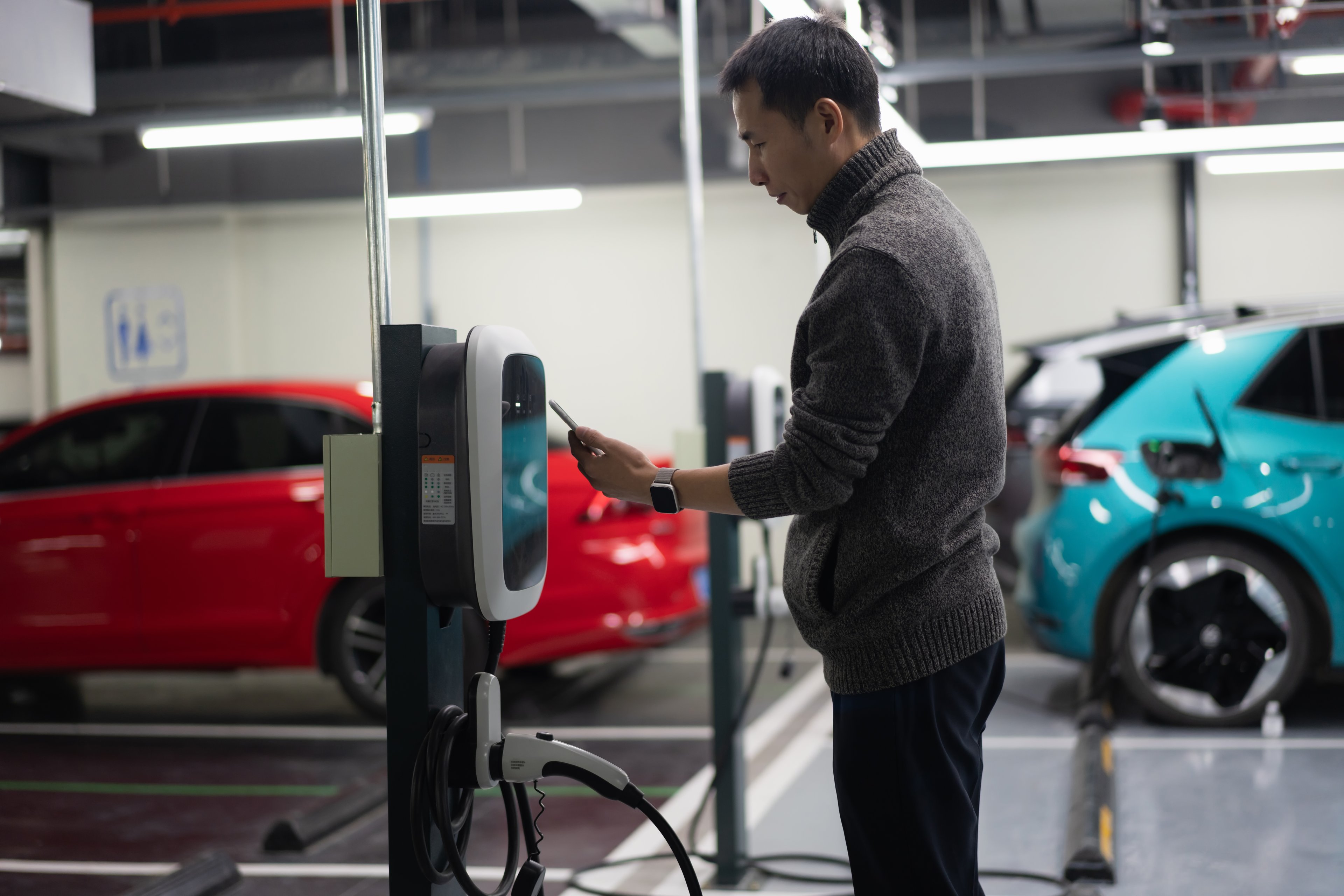 asian-man-plugging in electric vehicle
