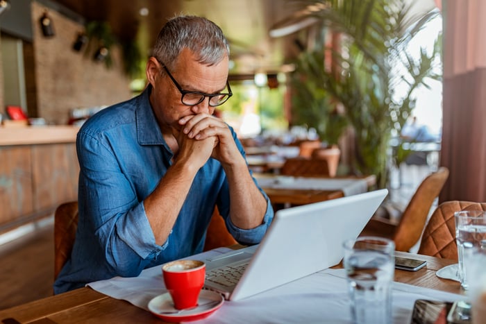 A person at a laptop with a serious expression.