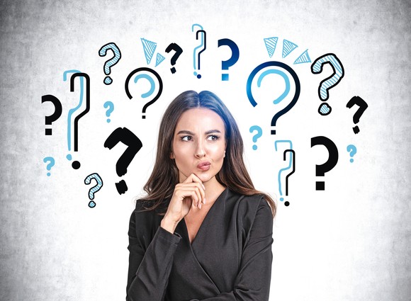 A person with their finger on their chin against a backdrop of illustrated question marks.