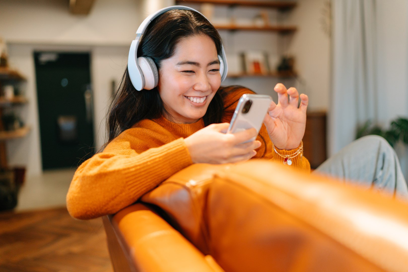 smiling at smartphone in orange couch