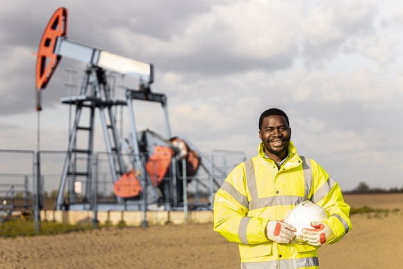 Oil field worker in front of a land-based oil rig.