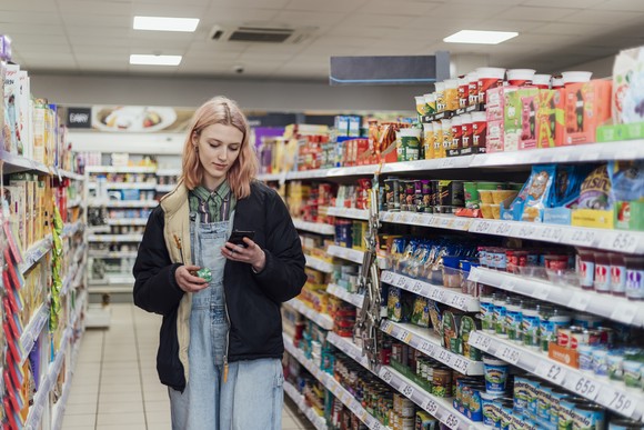Person looking at phone while standing in the aisle of a store.