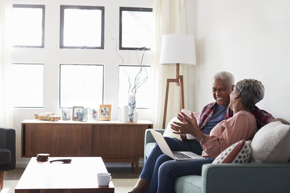 Two people sitting on a couch and smiling.