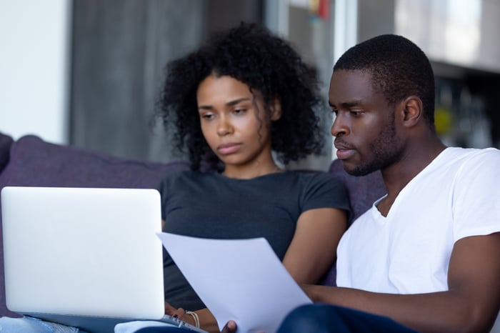 Couple looking at documents and laptop together.