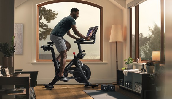 A person riding on a Peloton in a living room.