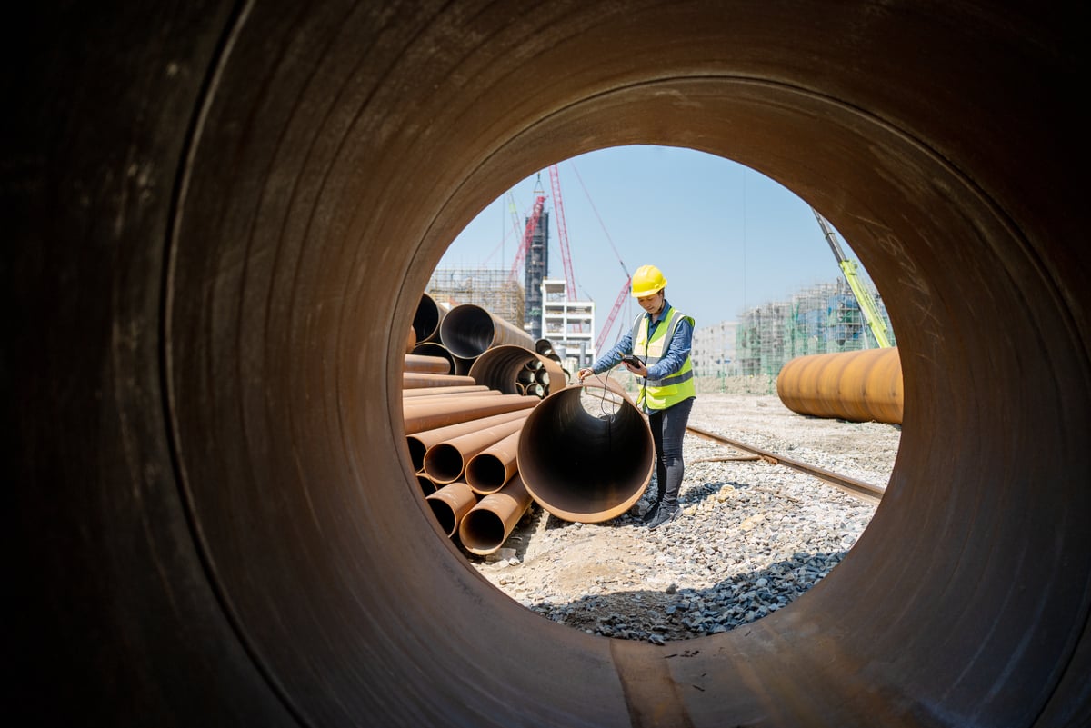 worker with pipe at construction site.