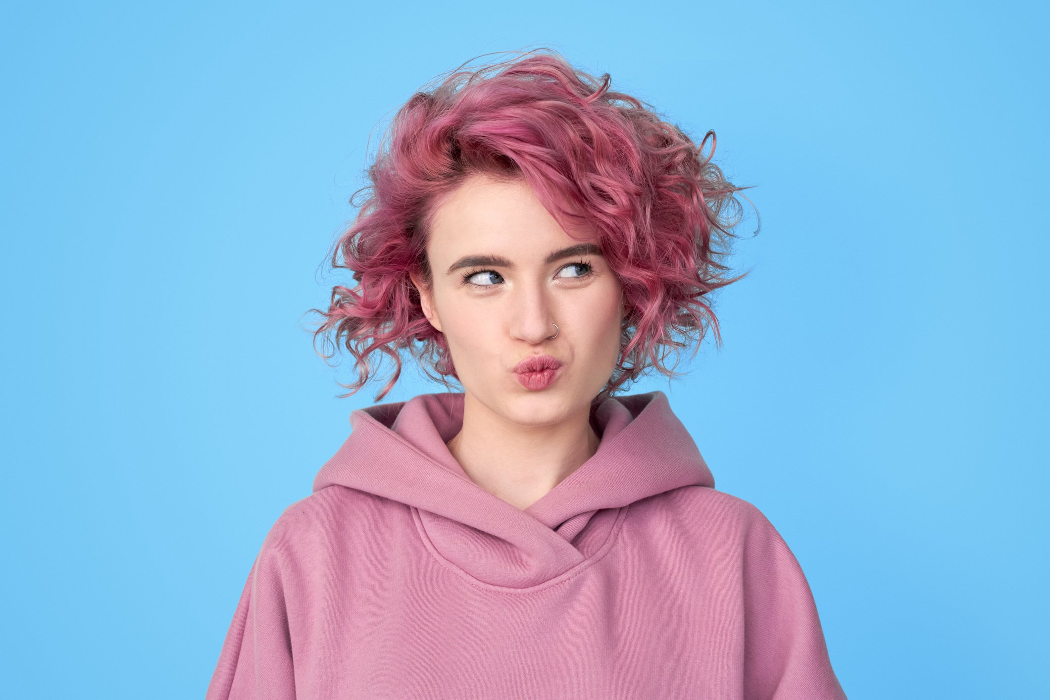 Person with pink hair looking thoughtful. 