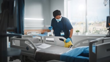 Hospital staff sanitizing a bed.