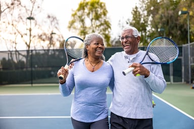 Laughing couple holding tennis rackets