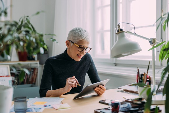 A person sitting at a table while using a tablet. 