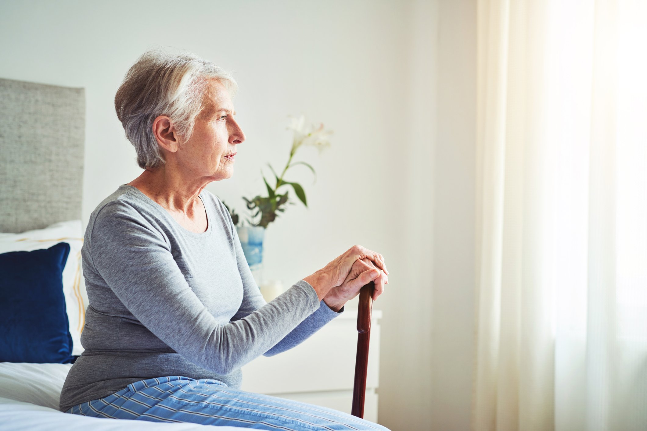 Elderly person sitting on a bed.