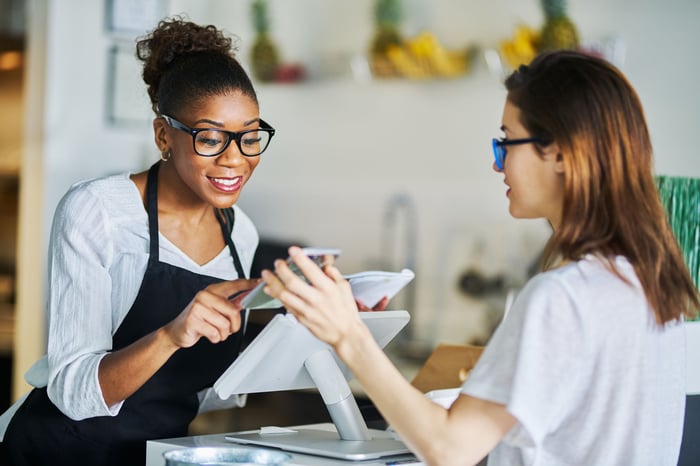 A restaurant owner using a Toast point-of-sale (POS) system to process a customer's payment. 