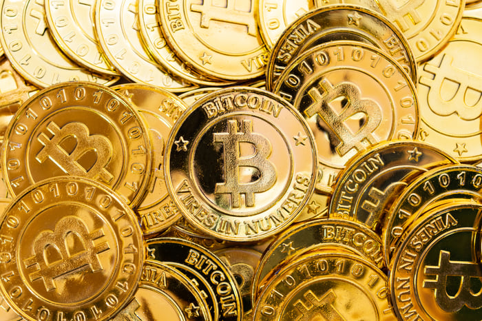 Pile of gold coins with Bitcoin logo.