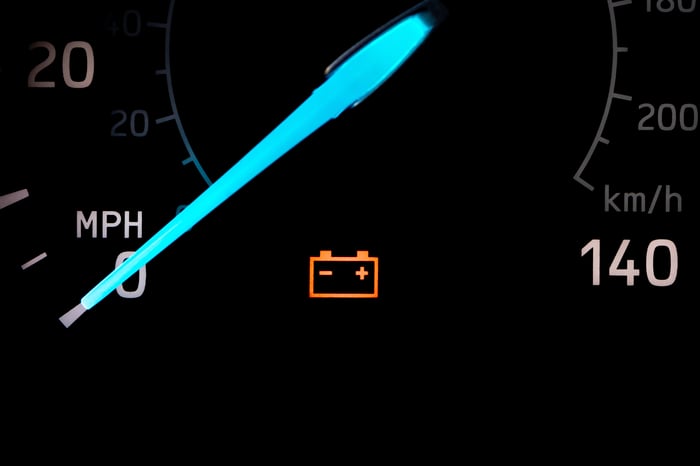 A dashboard on a car shows an orange low battery indicator underneath its speedometer.