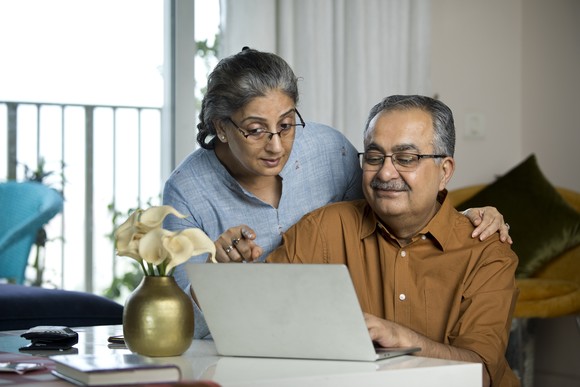 Two people at a laptop, one looking over the other's shoulder.