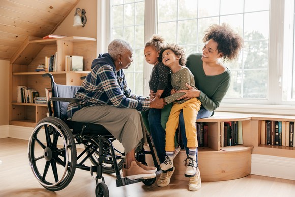 A person in a wheelchair with another adult and two children nearby.