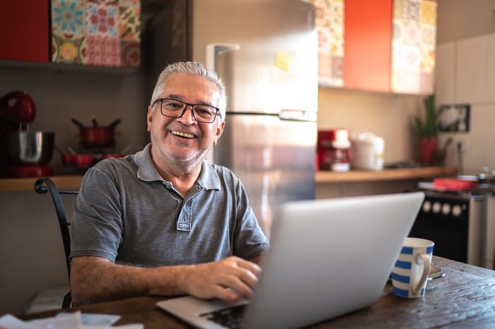 A smiling person at a laptop.