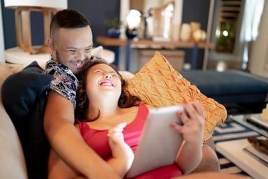 couple laughing couch tablet