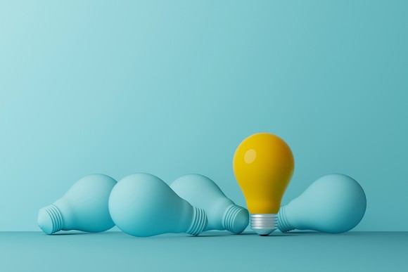 One yellow light bulb among a group of gray light bulbs.