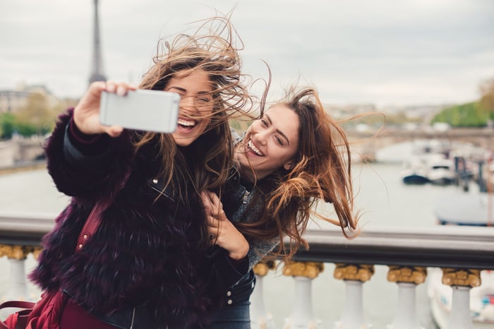 Two young people take a selfie on a Paris bridge. 