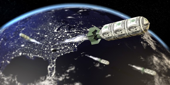 A rocket made out of dollar bills launches into orbit.