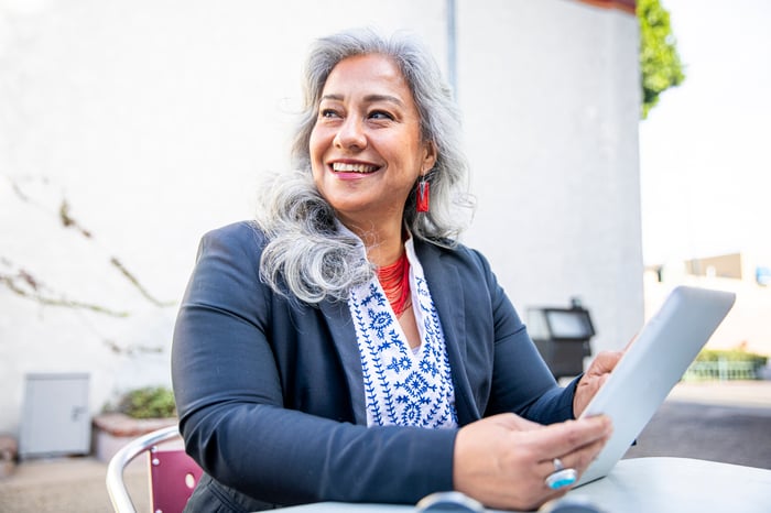 A smiling person holding a tablet.